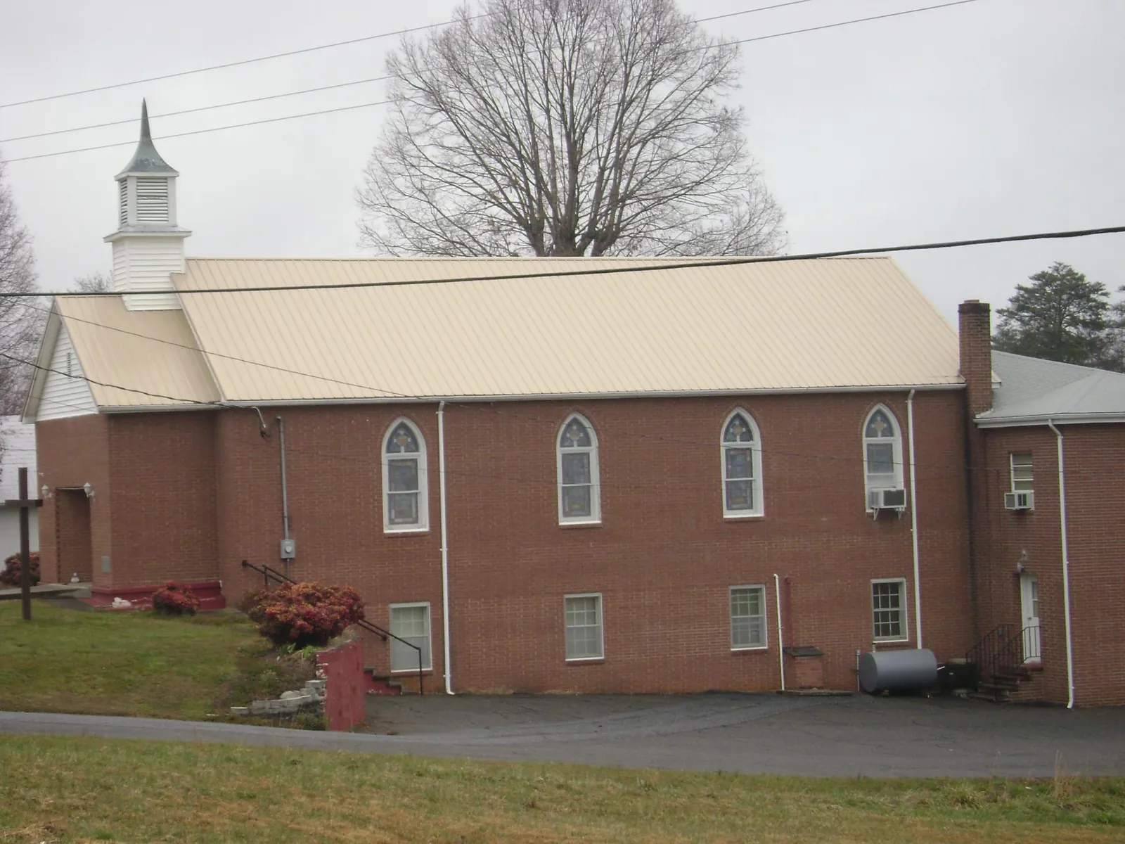 New tan metal roof on a brick church with a white steeple in Milton